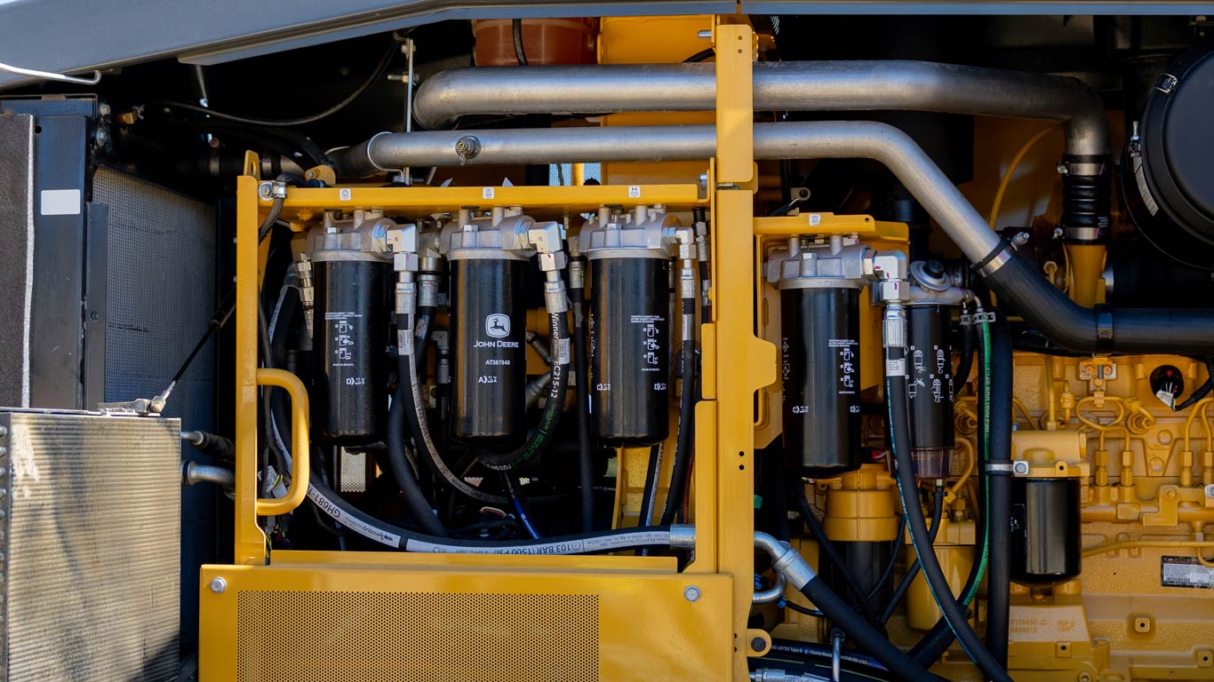 Close-up of maintenance filters and fluid system components inside a John Deere motor grader.