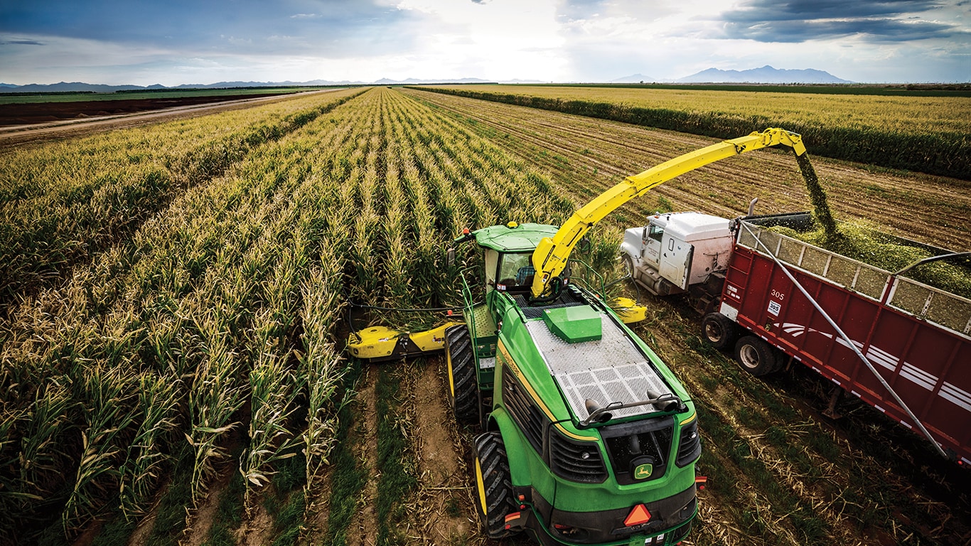 a combine harvesting a field and pouring its contents into a truck