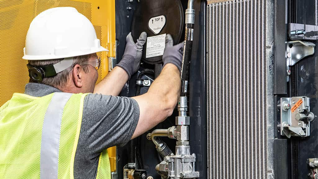 John Deere engine distributor working on industrial engine inside a piece of equipment