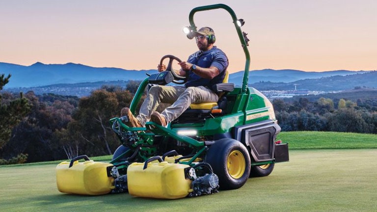 person on mower on golf course