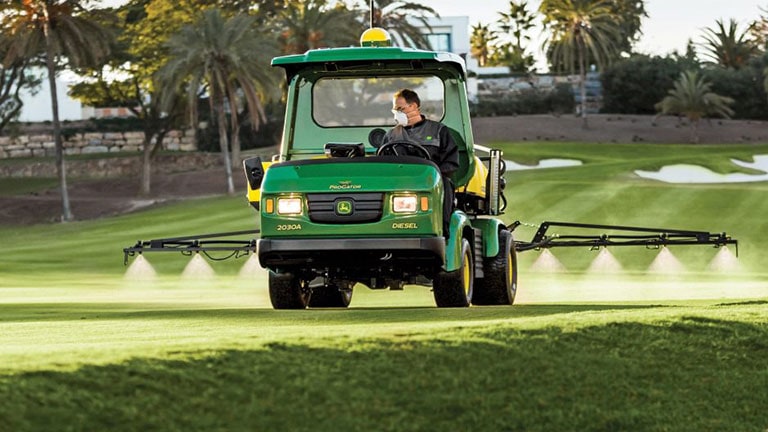 person riding sprayer on golf course