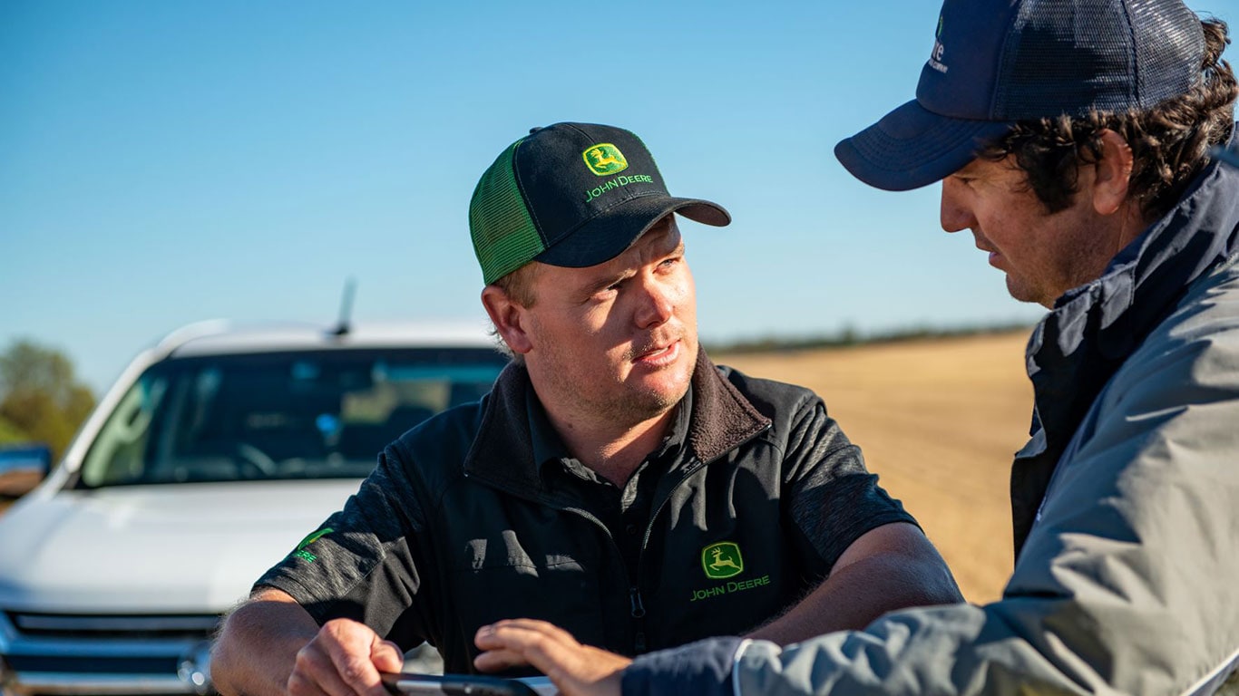 Two men looking at a tablet in a field