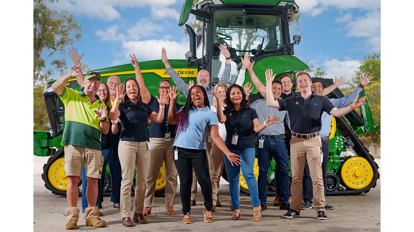 Employees of John&nbsp;Deere looking excited in front of 9RX Tractor.