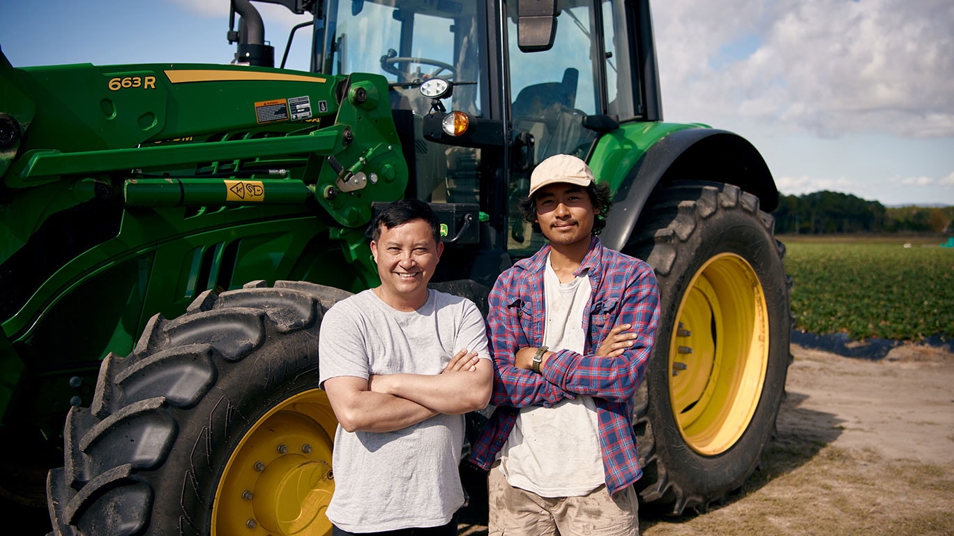 George and his son Jet on their strawberry farm in front of John&nbsp;Deere tractor