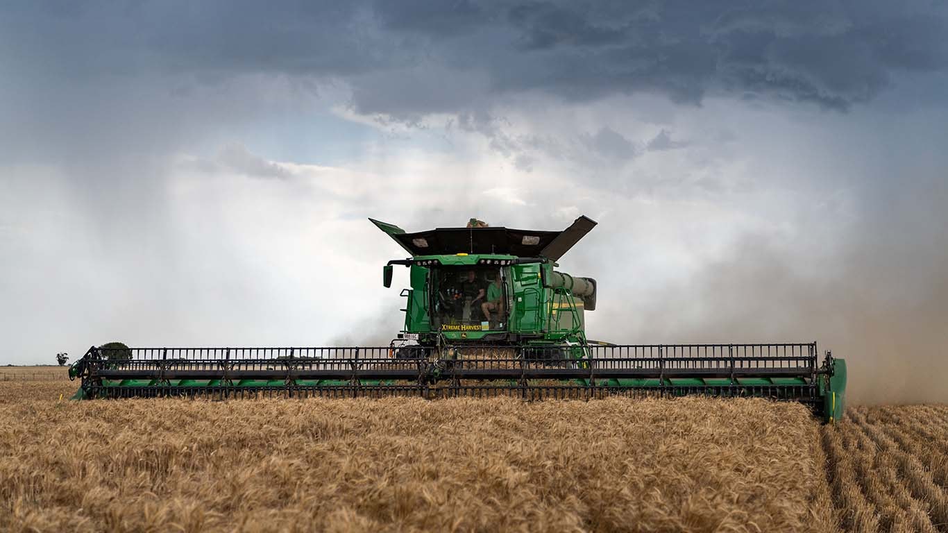John Deere X9 Combine Harvester in a wheat field with stormy sky