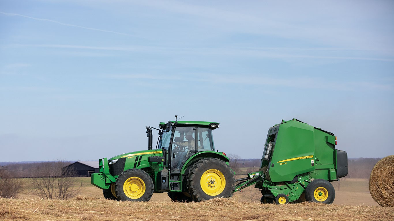 Tractor driving away from hay bail.