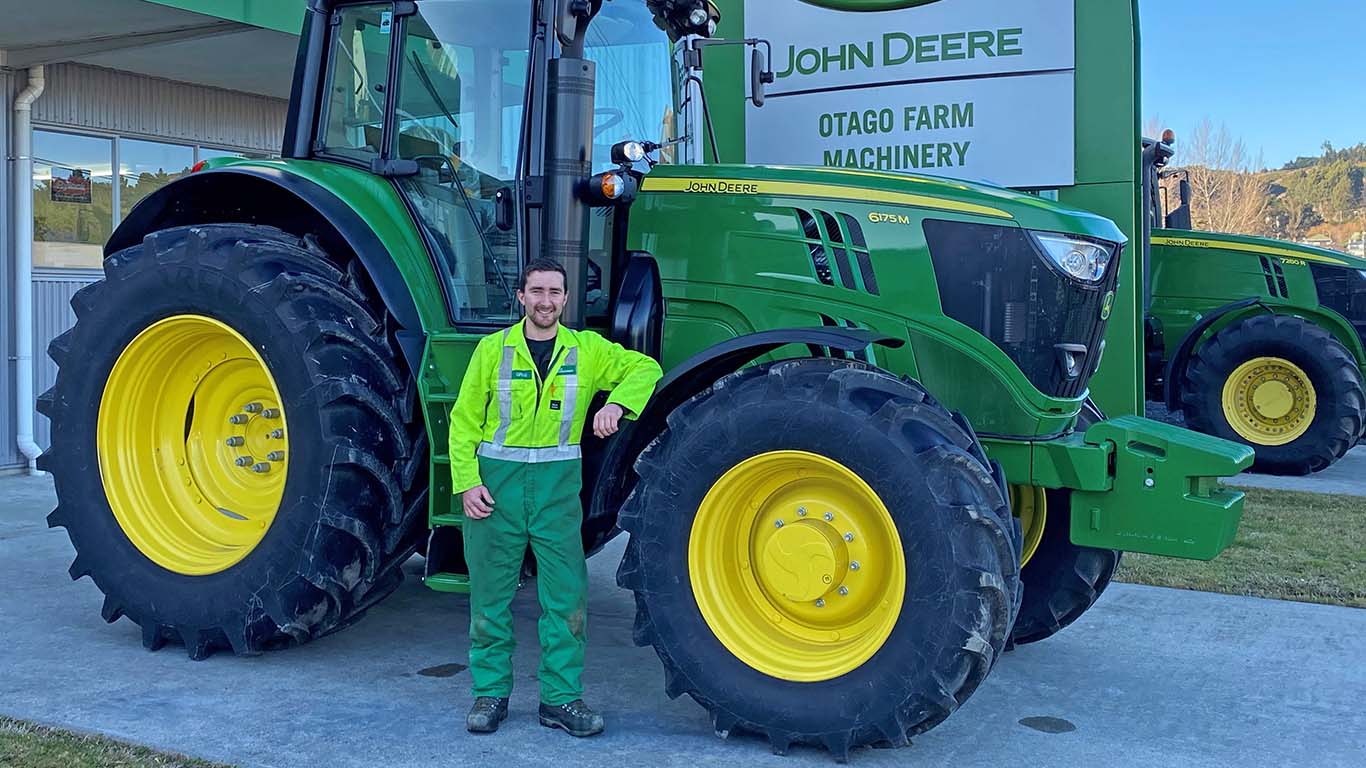 Greg Bishop standing next to a tractor outside a dealership.