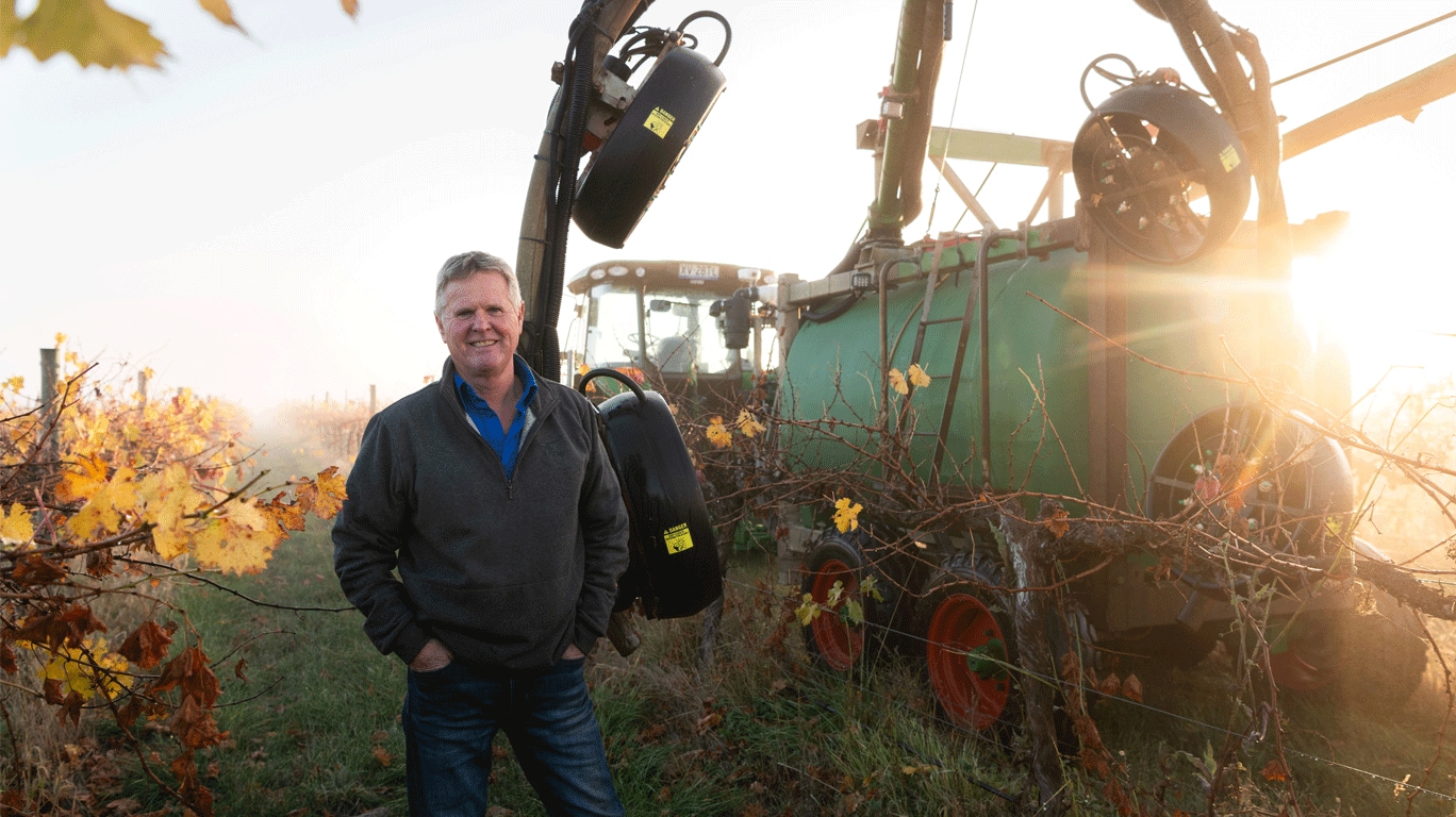 Ben Thomson standing by tractor during sunset in farm field