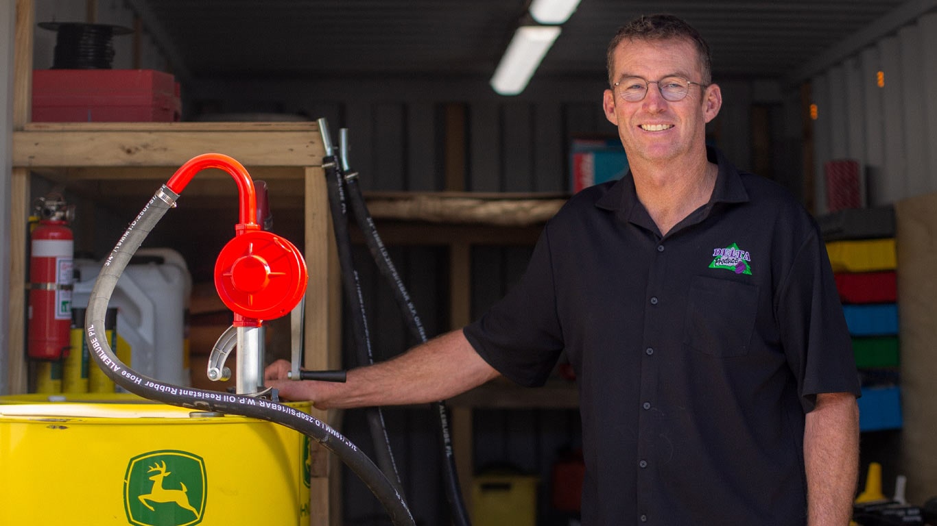 Farmer Evan Paxton standing next to a large 205-liter drum of Plus-50 II oil. He's smiling at the camera.