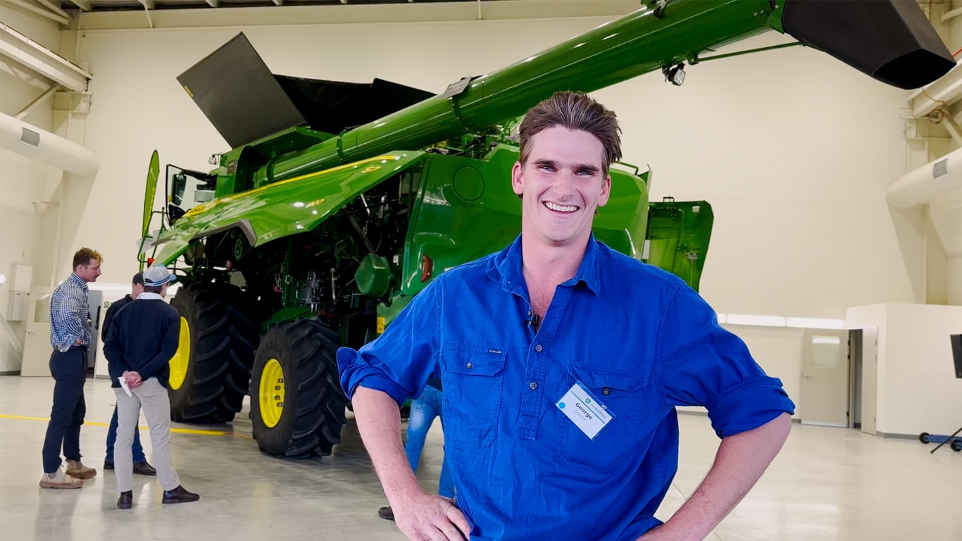 Young smiling farmer in front of a John Deere Combine