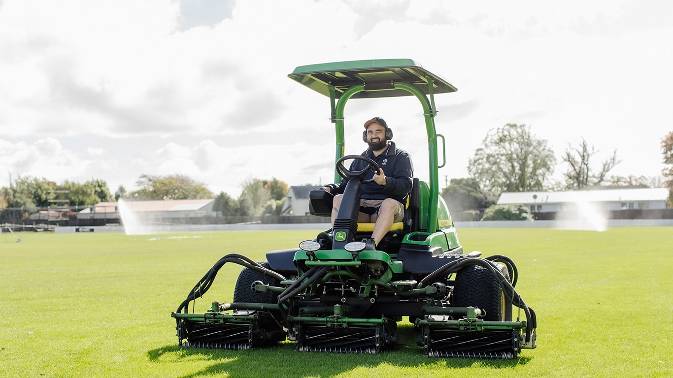 Steve sits on the John Deere 7700APrecisionCut™ Fairway Mower in an open sports turf field