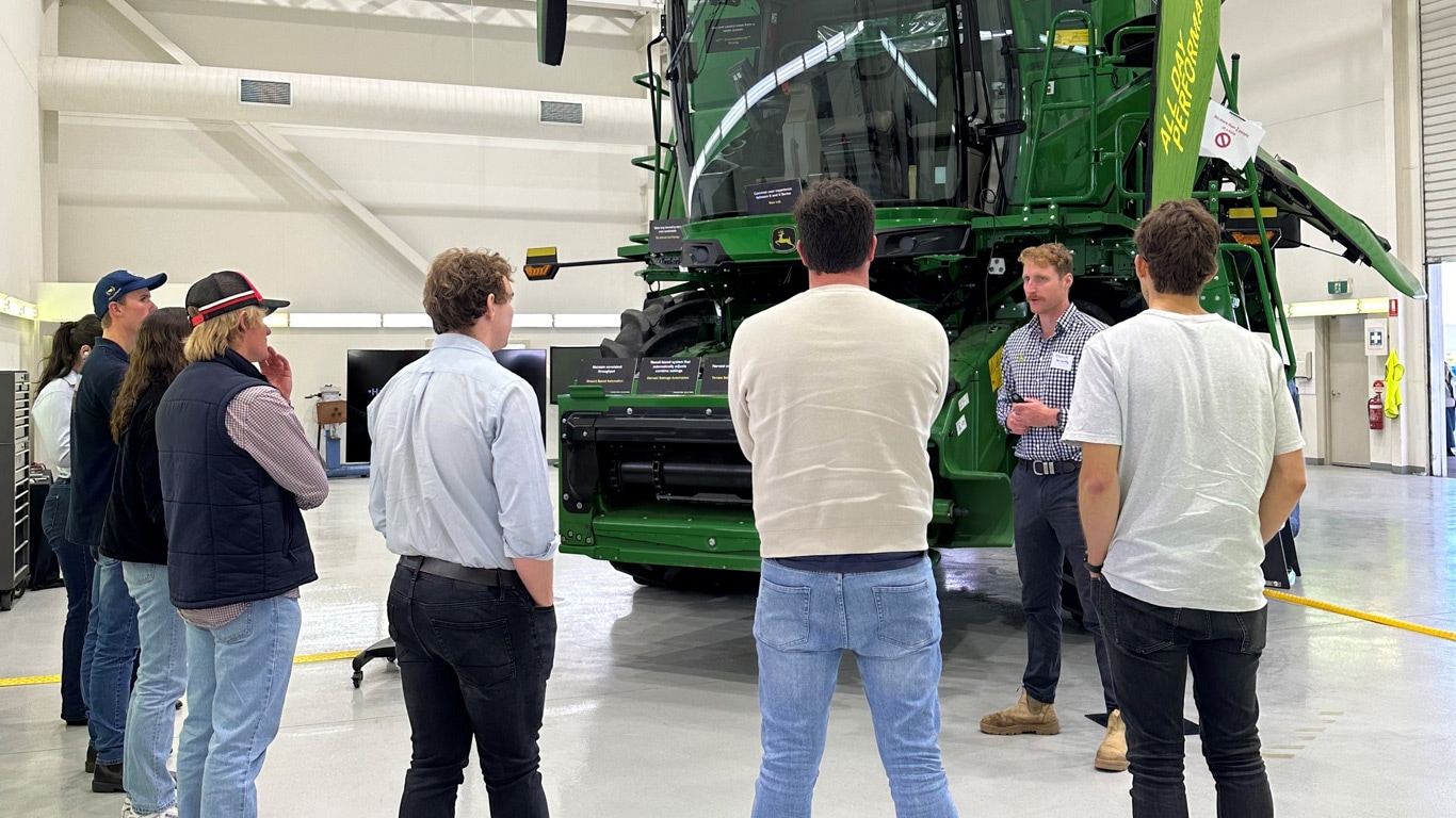 Young farmers looking at a John Deere Combine