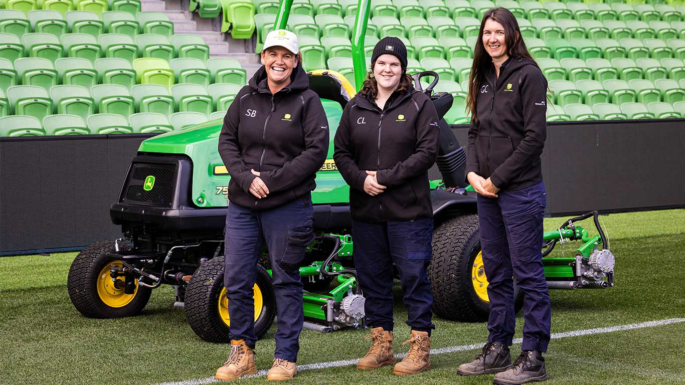 Women in Turf volunteers standing in front of equipment at Melbourne Rectangular Stadium (left to right): Sally Benwell, Codi Long, Georgie Chandler.