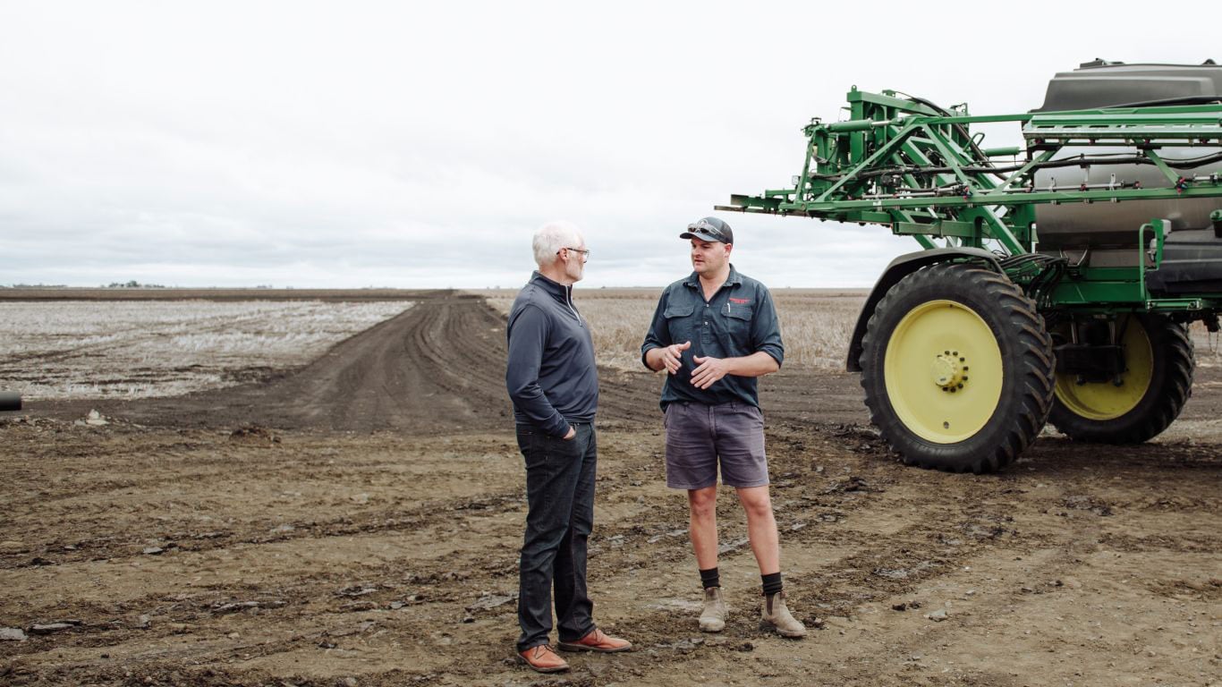 Two men talking in a ploughed paddock.
