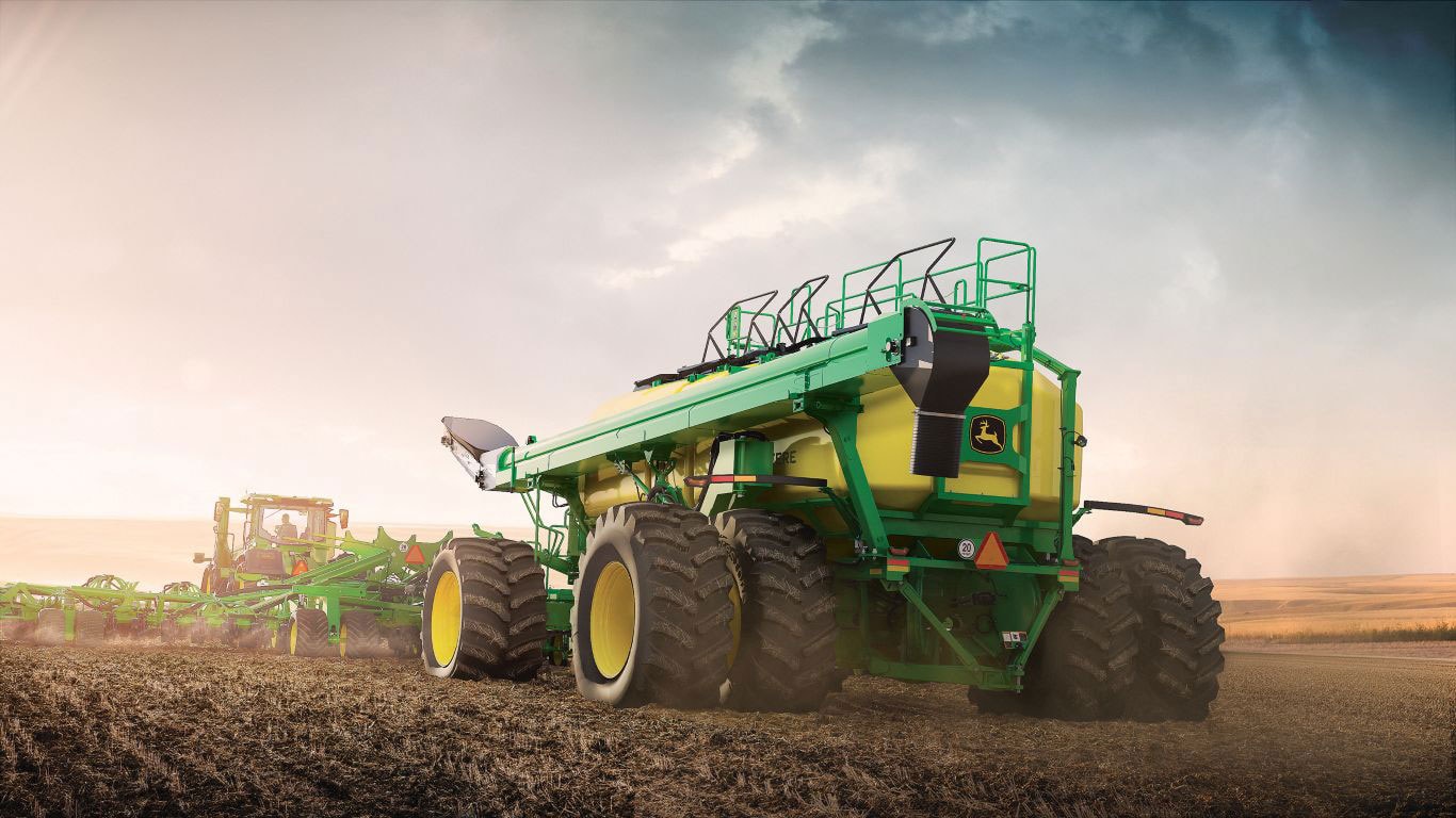 Large green and yellow machine with black and yellow wheels in paddock with stormy sky