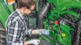 Woman performing maintenance on John Deere tractor