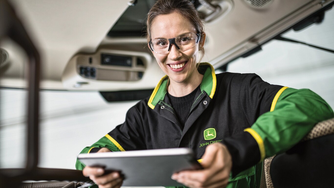 a woman with safety glasses smiling while holding a tablet