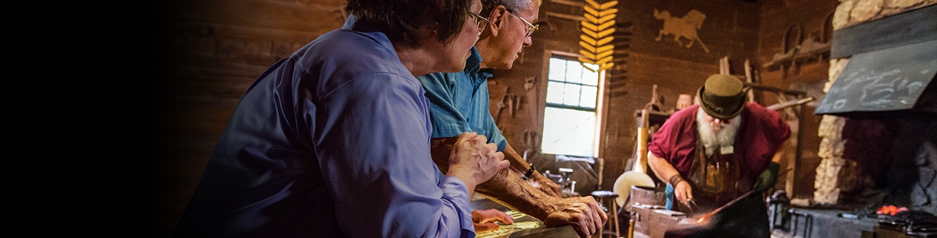 Older couple watching the blacksmith a piece of metal hammer at the Historic Site in Grand Detour, Illinois, United States