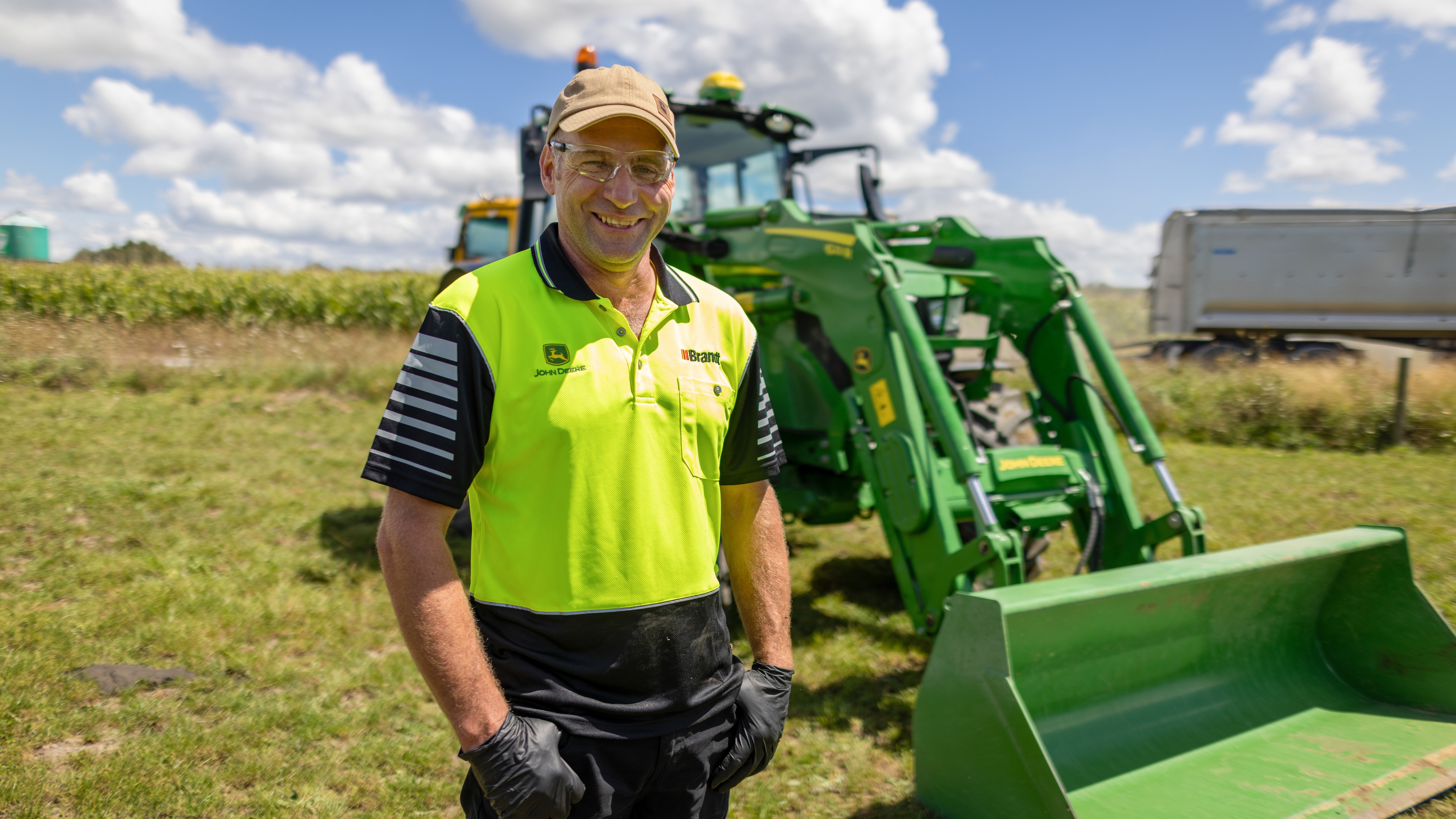 Bryce smiling in a field in front of a tractor