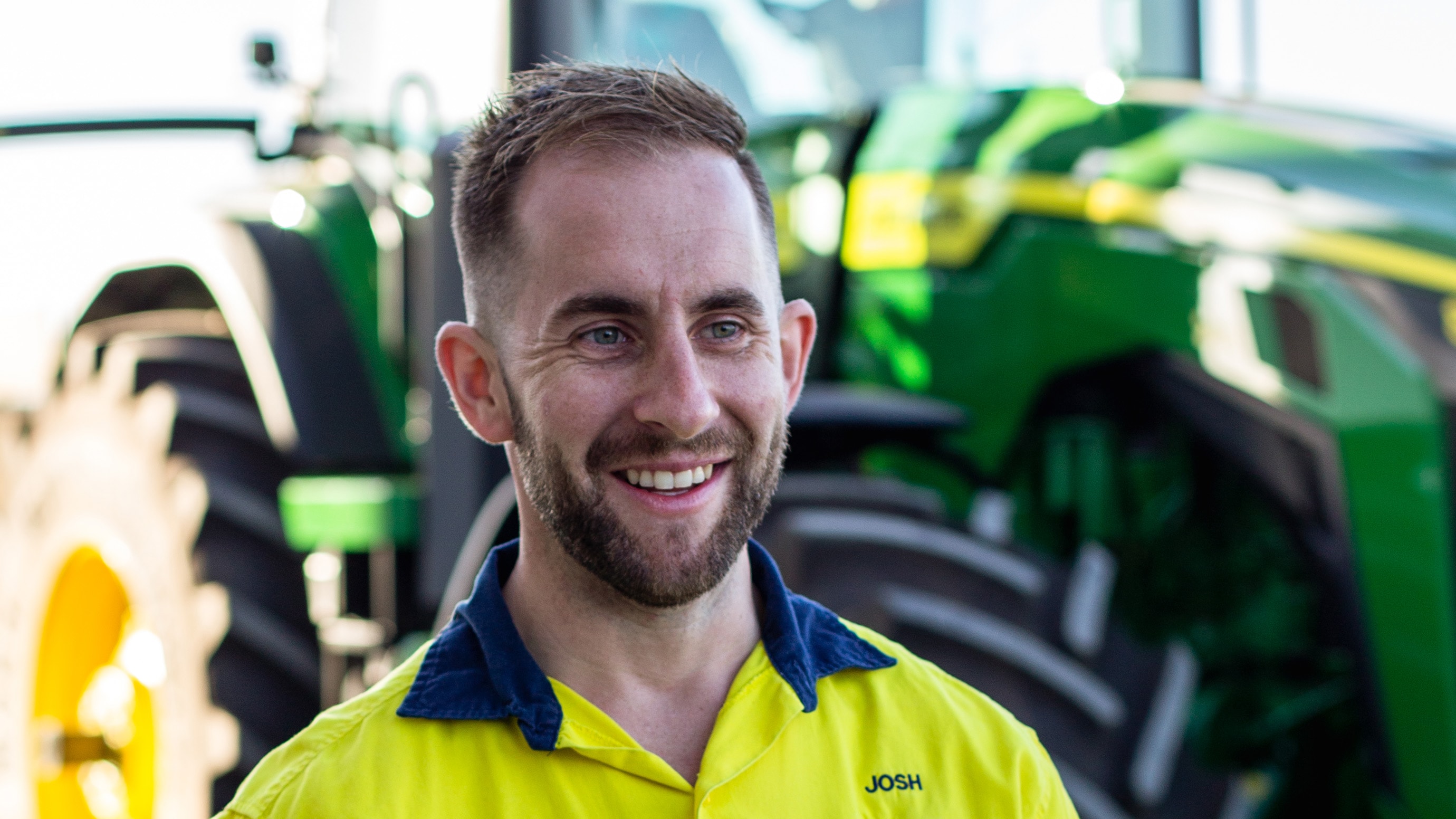 Josh smiling outside in front of a tractor