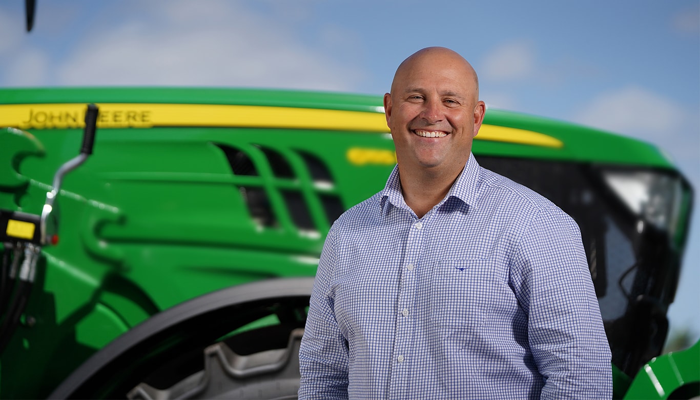 Luke Chandler smiling in front of a tractor