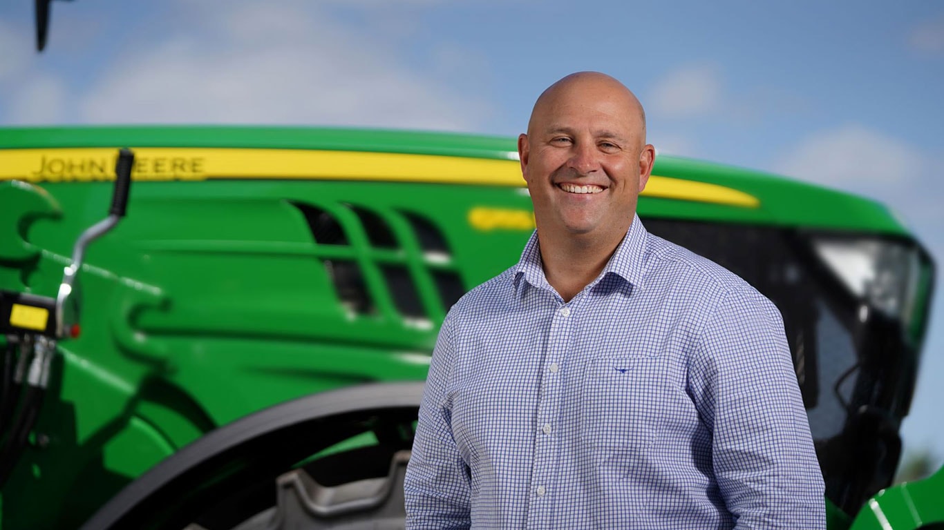 Photograph of a man in front of John Deere equipment