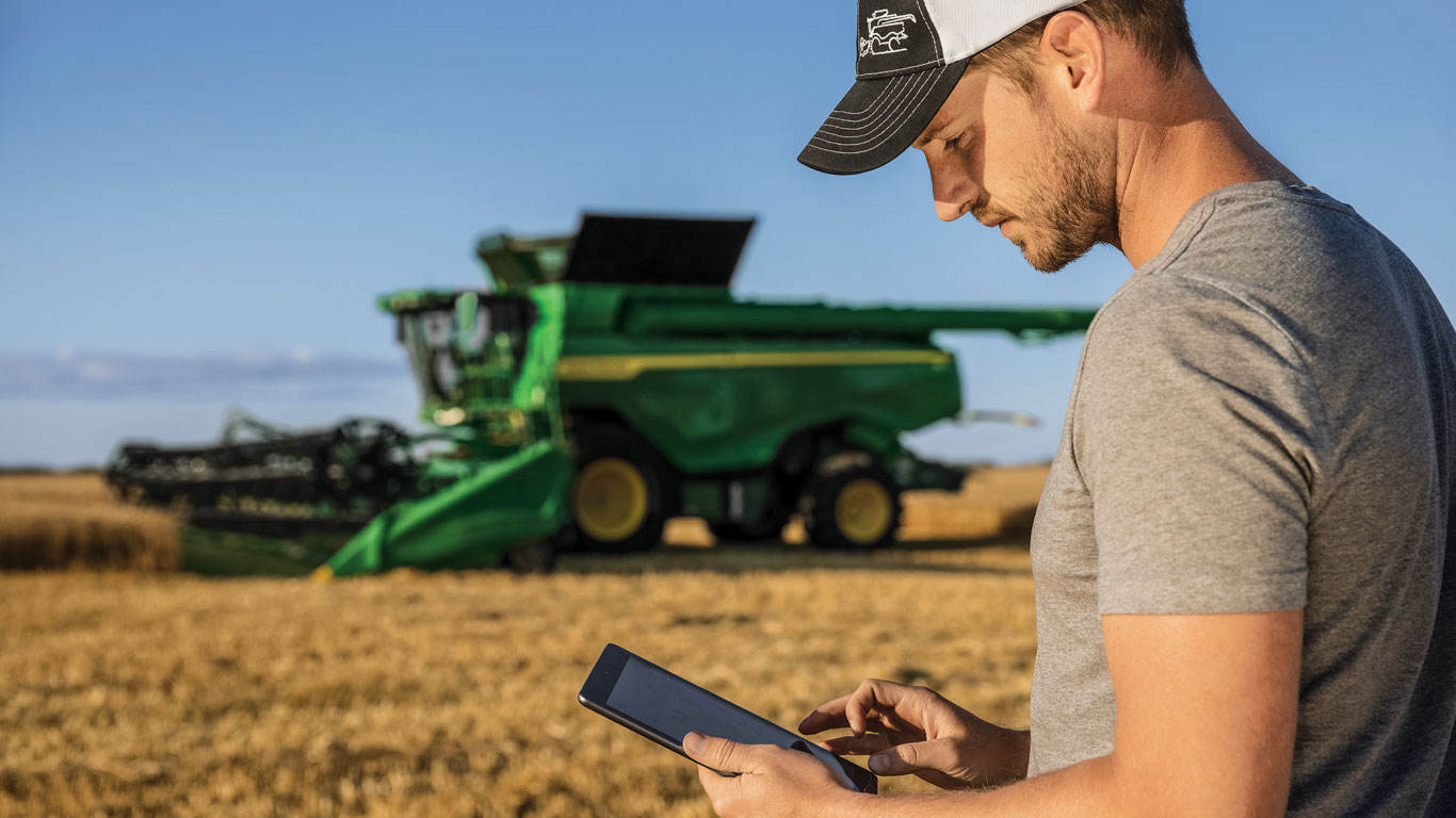 Man with a tablet in a field in front of a combine