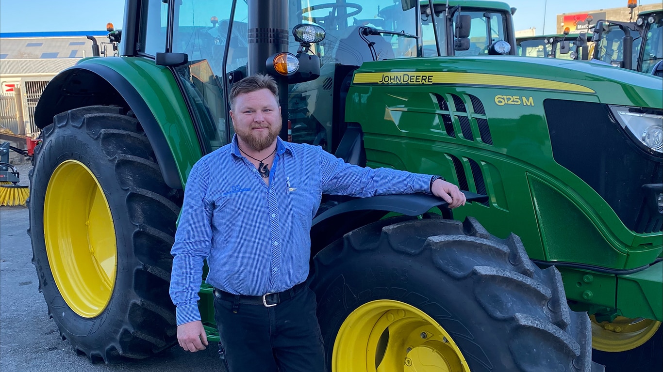 Jimmy O'Donnell posing in front of John&nbsp;Deere equipment