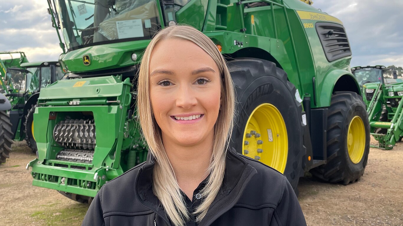 Sarah smiling standing in front of 9900 self-propelled forage harvester