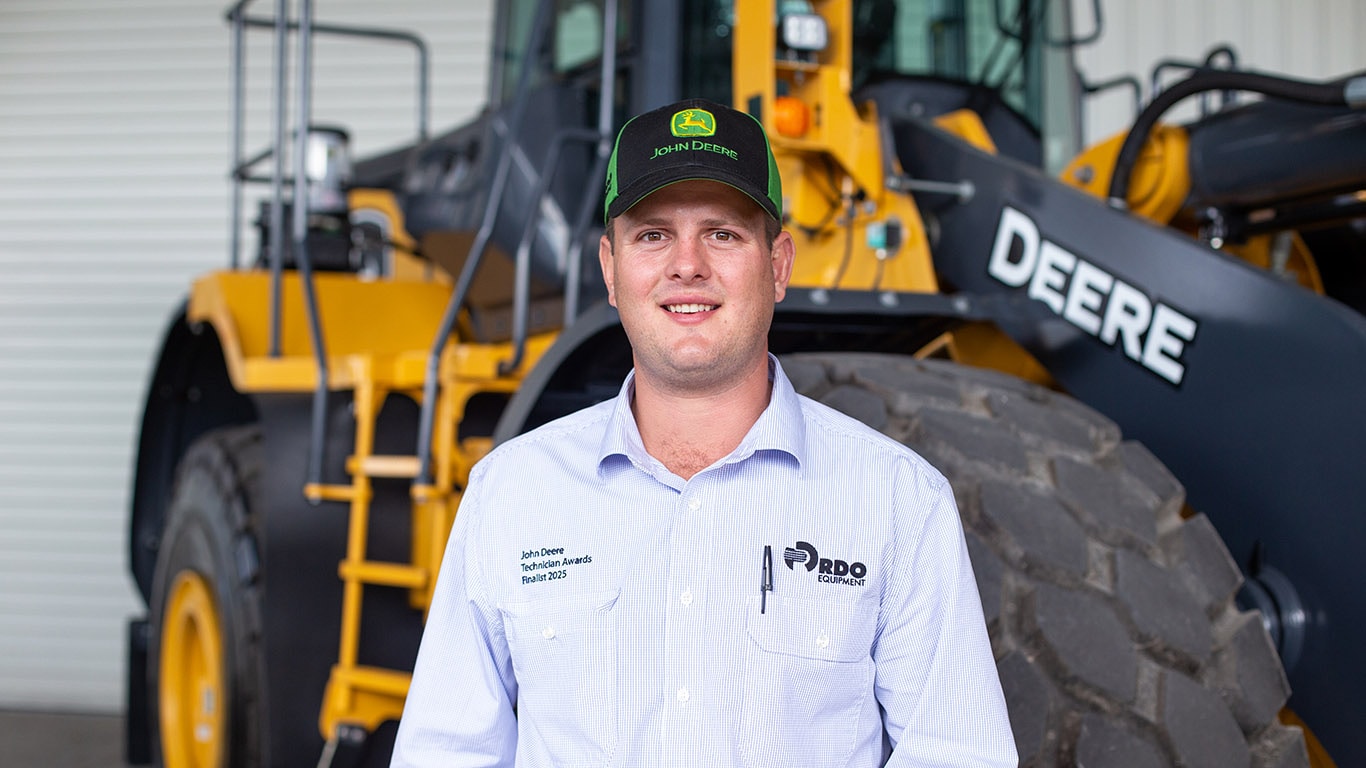 Damian standing in front of John Deere construction equipment