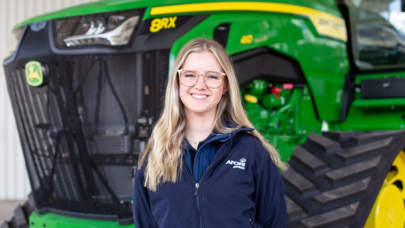 Poppy standing to the left of a 9RT series tractor