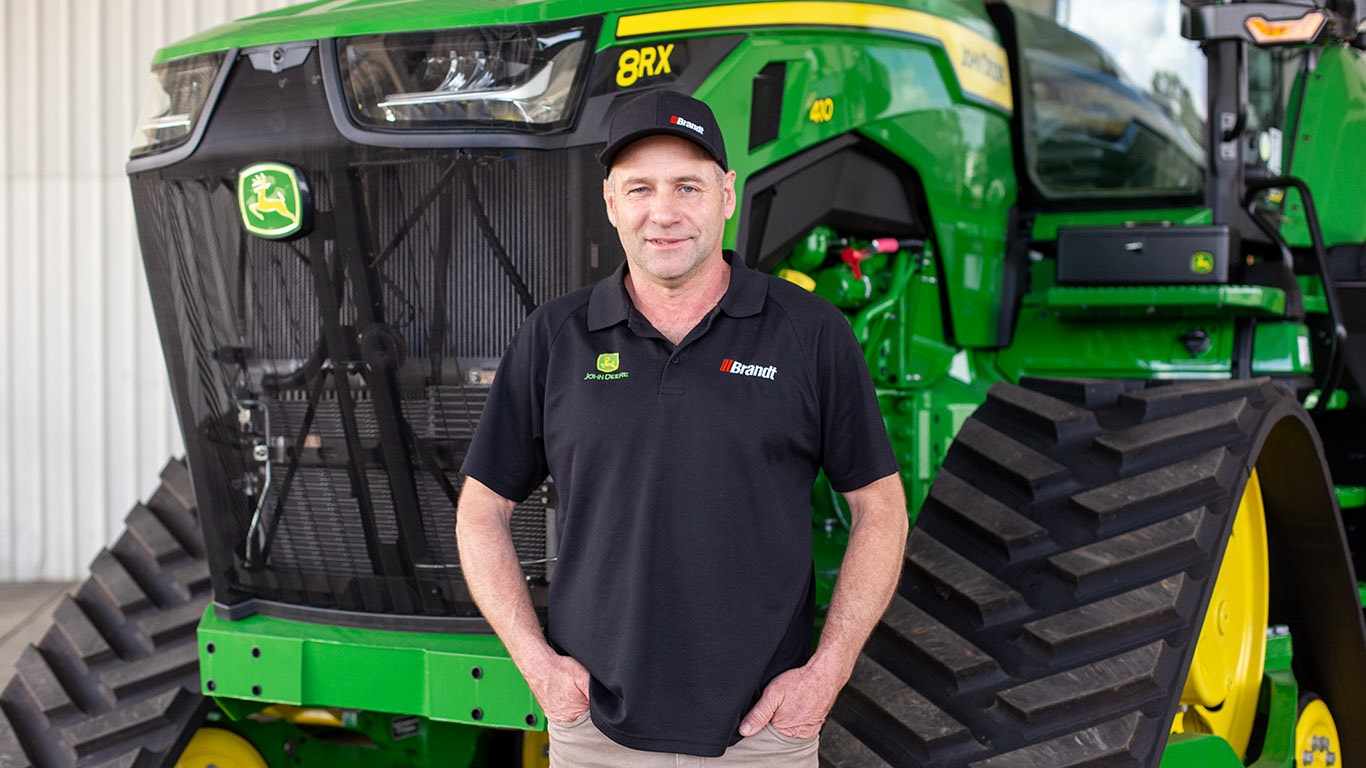 Bryce leaning on John Deere equipment