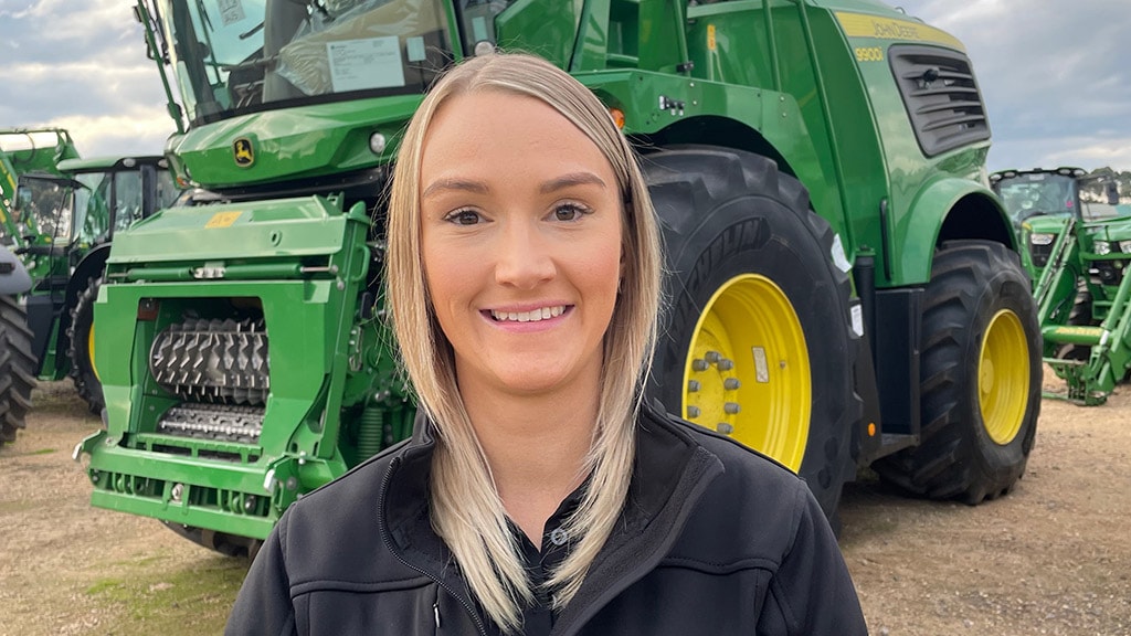 Sarah smiling standing in front of 9900 self-propelled forage harvester