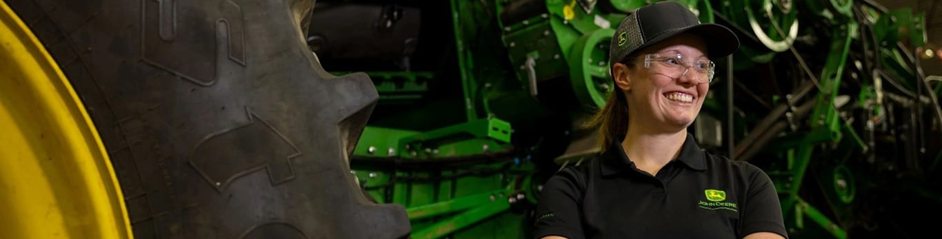 woman smiling with crossed arms next to a tractor