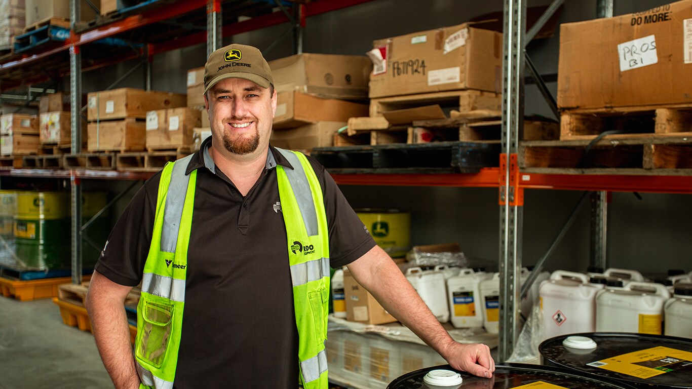 Troy smiling while leaning on a barrel inside a warehouse