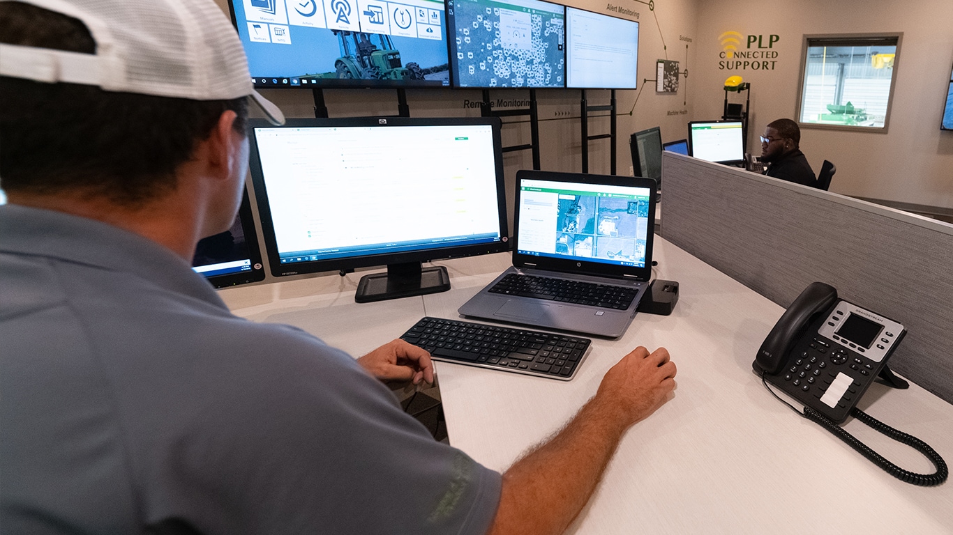 man at a desk looking at two monitors