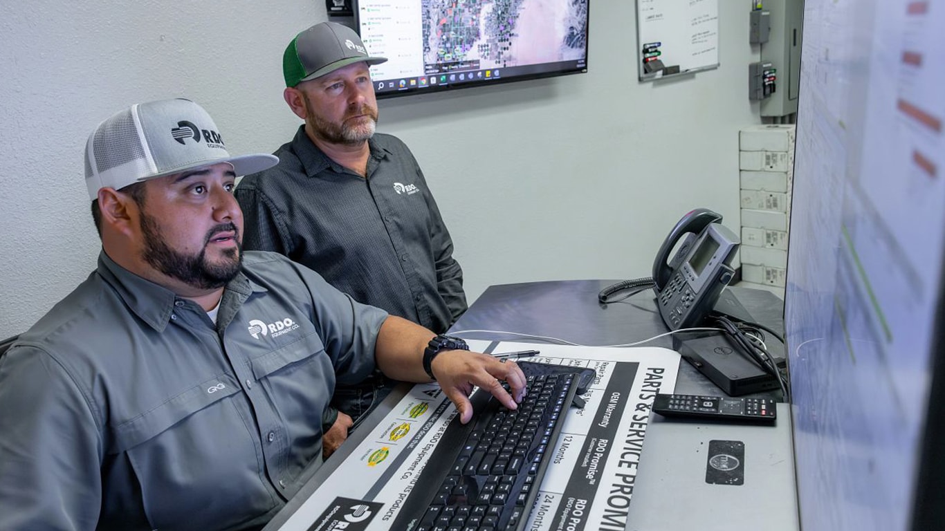Two dealership technical communicators are looking intently at a monitor seemingly trying to resolve an issue.