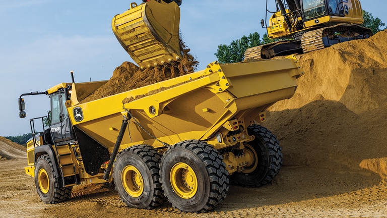 An excavator dumping dirt into a 260P Articulated Dump Truck.