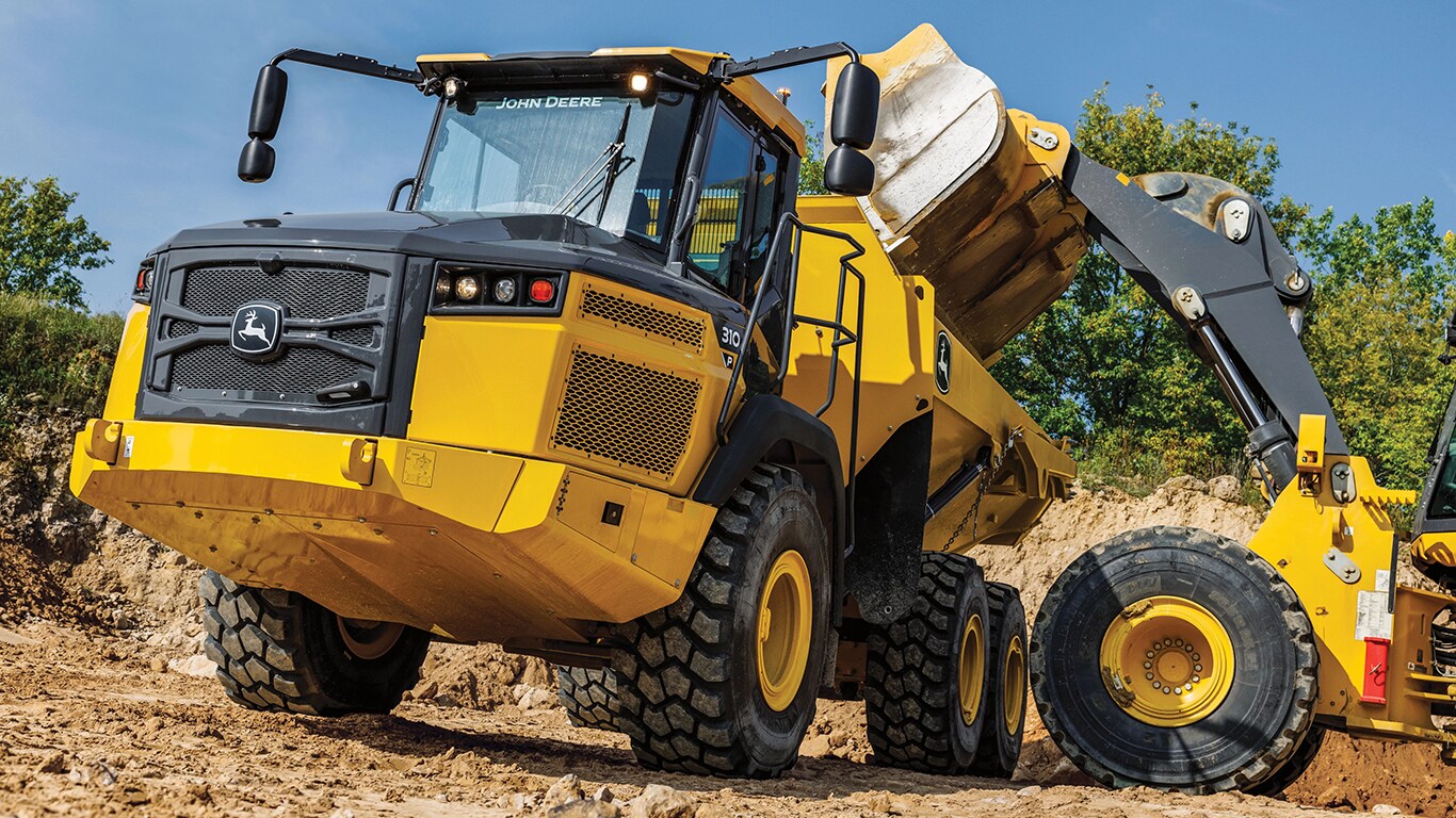 A wheeled loader dumping dirt into a 310P Articulated Dump Truck.