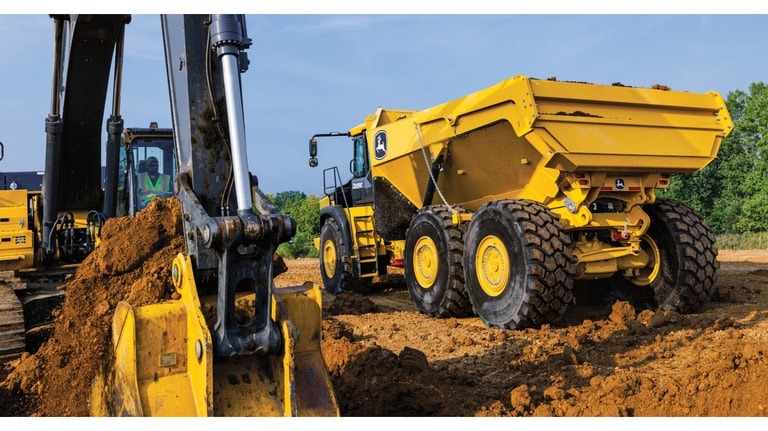 A 410P Articulated Dump Truck waiting to be loaded with dirt from a nearby excavator.