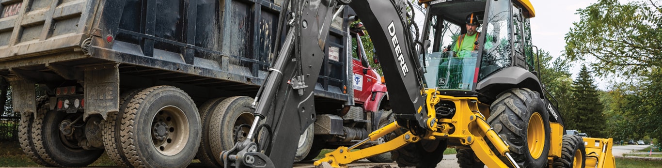 John Deere Backhoe hauling dirt on construction site