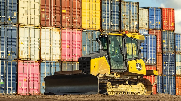 550P Dozer in front of a wall of colorful shipping containers.