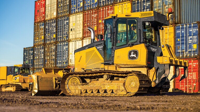 Left-side view of a 650P Dozer in front of a wall of colorful shipping containers.