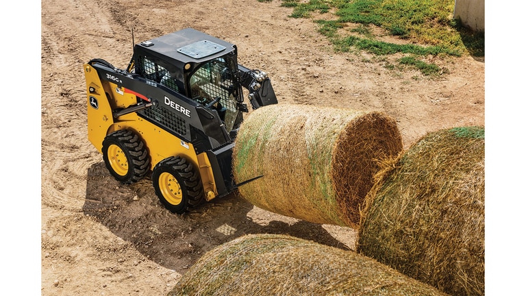 A 316G Skid Steer with bale spear attachment moving a hay bale.