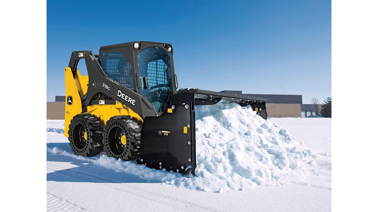 A 318G Skid Steer moves rock and dirt on unleveled terrain.