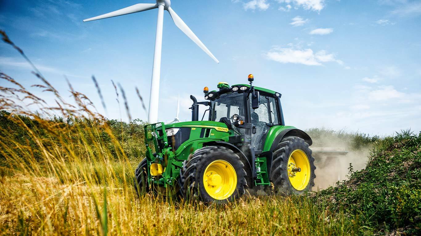 6M tractor in a field with a wind turbine in the background