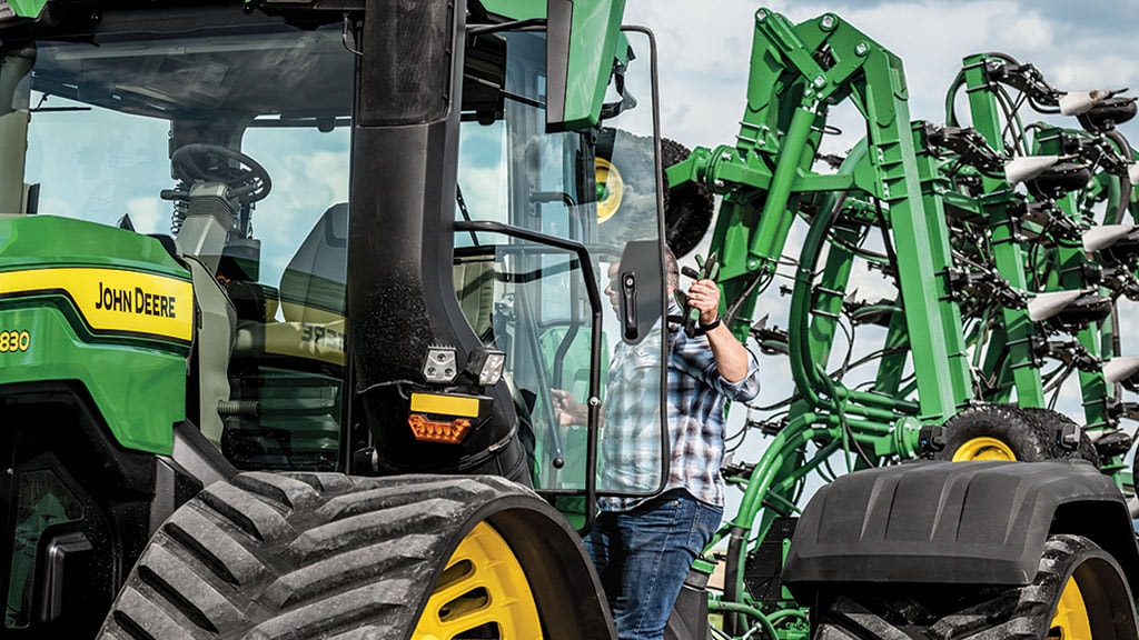 Man entering cab of 9RX 830 with folded tillage tool