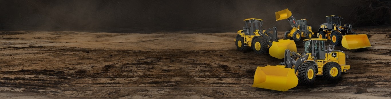 Several construction vehicles with yellow buckets on a dirt surface, showcasing heavy machinery.
