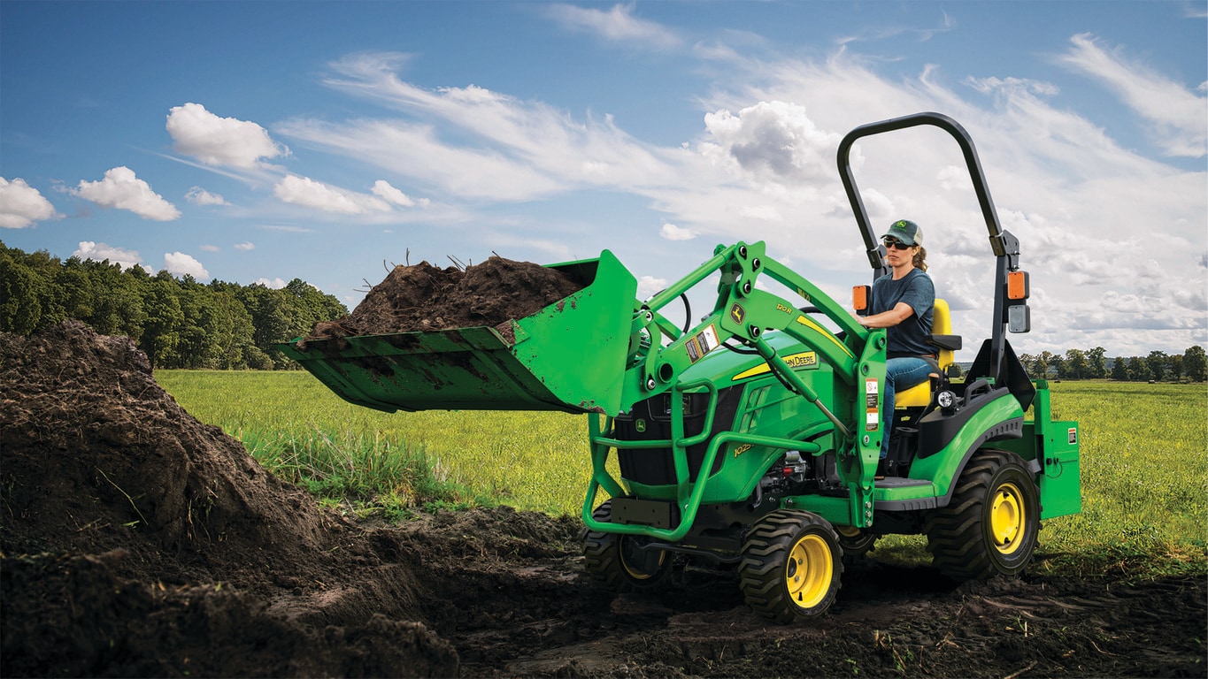 person using 1025R tractor to scoop dirt in field