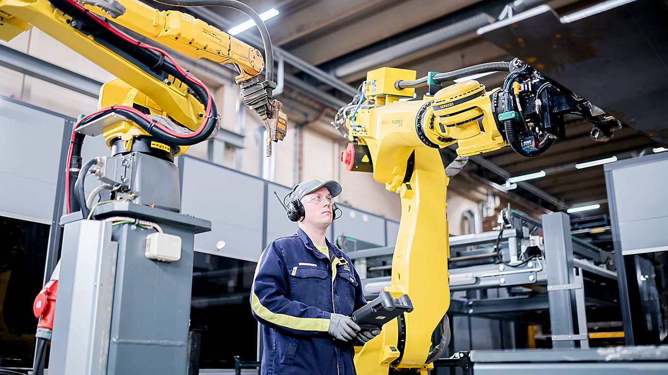 Jarkko Tuononen guiding a robot in the factory